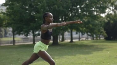 Spor kıyafetli genç bir kadın parkta yoga egzersizleri yapıyor.