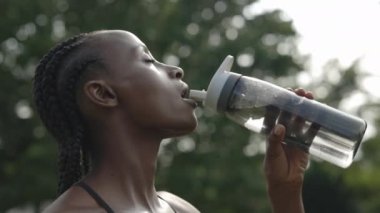 Afro örgülü kadın eğitimden sonra suyla ferahlatıyor.