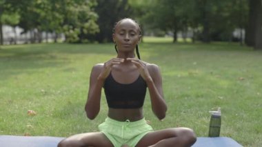 Şehir parkında meditasyon yapan sağlıklı bir kadın.