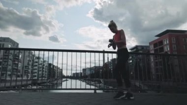 Son sınıf öğrencisi kadın bileğinde akıllı saatle sokakta koşuyor.