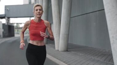 Sportif yaşlı kadın sokakta sabah koşusu yapıyor.