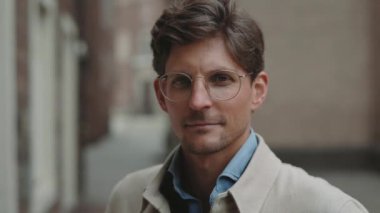 Şehir caddesinde duran ve kameraya bakan bir iş adamı.