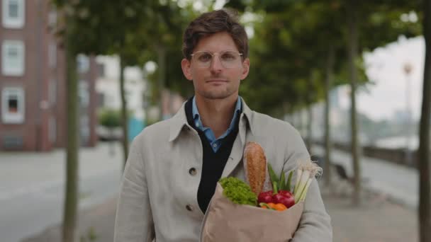 Mature man standing on street and holding grocery bag — Stock Video