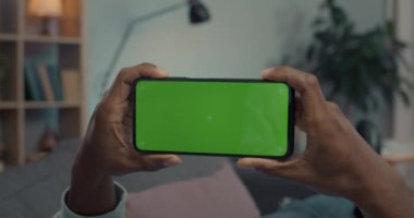 Evde yeşil ekranlı cep telefonu kullanan Afrikalı bir adam