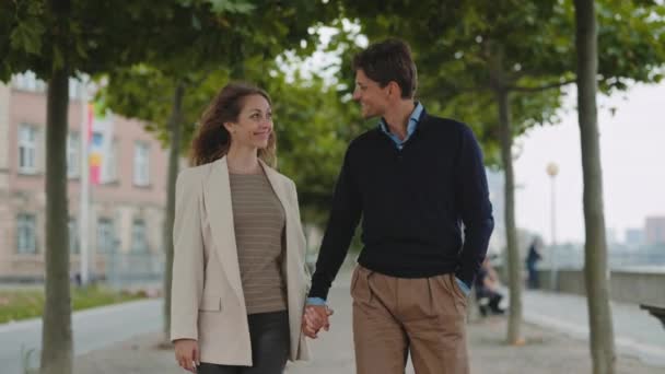 Smiling mature couple holding hands and walking outdoors — Stock Video