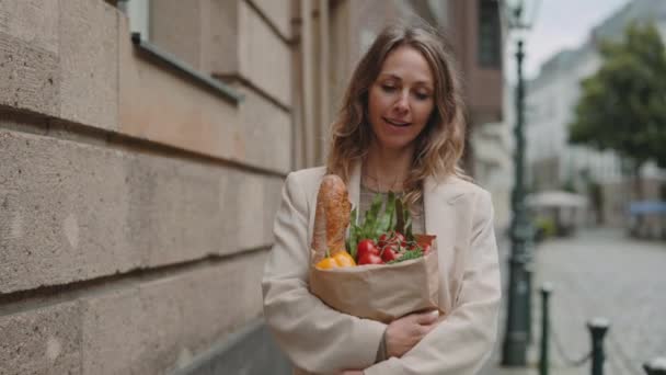 Mujer llevando papel bolsa de compras con comida al aire libre — Vídeos de Stock