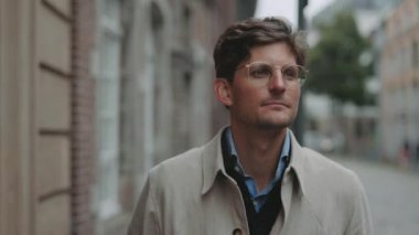 Gözlüklü, caddede yürüyen beyaz, olgun bir adam.