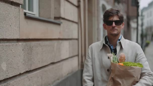 Hombre con discapacidad visual llevando bolsa de comestibles al aire libre — Vídeos de Stock