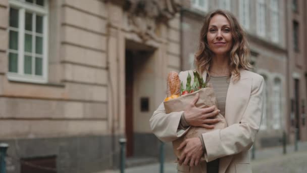 Lady håller matsäck och ler på kameran utomhus — Stockvideo