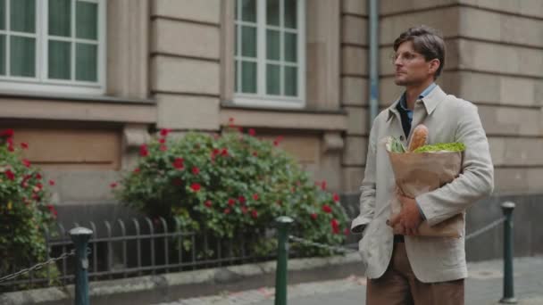 Mature man carrying paper bag with food outdoors — Stock videók