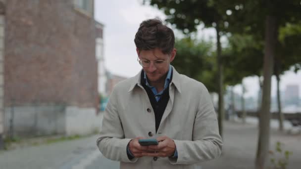 Biznesmen korzystający ze smartfona podczas spaceru na świeżym powietrzu — Wideo stockowe