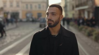 Young bearded man dressed in stylish outfit walking outdoors