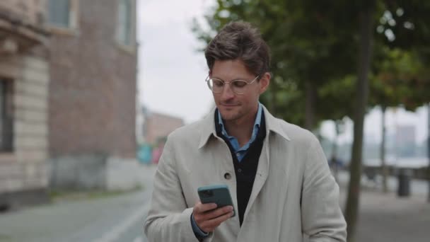 Reifer Mann läuft mit Smartphone in der Hand auf der Straße — Stockvideo