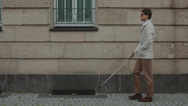 Visually challenged man walking with cane outdoors — Stock Video