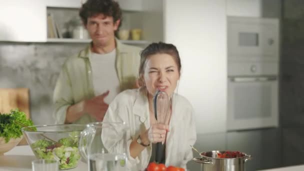 Сумасшедшая молодая пара готовит на кухне с песней и танцами — стоковое видео