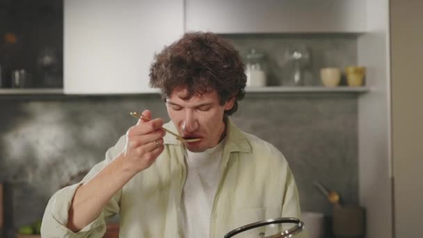 Man preparing dish on kitchen and trying taste from spoon — Videoclip de stoc