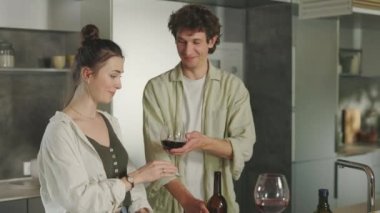 Mutlu çift yemek pişiriyor ve kırmızı şarap içiyor.