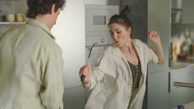 Neşeli aile yemek yaparken dans edip şarkı söylüyor.