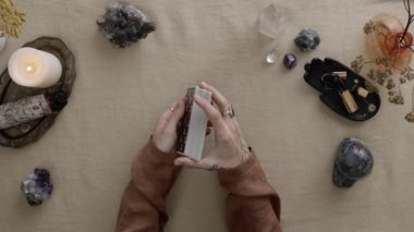 New York, ABD - 1 Mayıs 2021: Tarot kartlarını seçen tarot okuyucusunun üst görüntüsü. Tarot kartları yanan mumların yanında masanın üzerinde duruyordu. Fal tahmini kavramı.