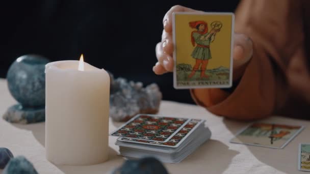 New York, États-Unis - 1er mai 2021 : diseur de bonne aventure caucasien montrant la carte à l'appareil photo tout en lisant les cartes de tarot aux chandelles. Les prédictions du destin et une séance magique sur le concept des cartes. — Video