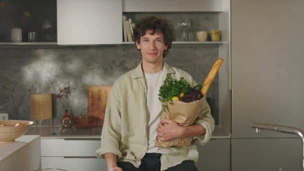 Retrato del hombre sosteniendo la bolsa de comestibles en la cocina moderna — Vídeos de Stock