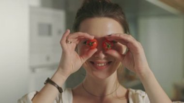 Mutlu kadın evde gözleri kiraz domatesiyle kaplıyor.