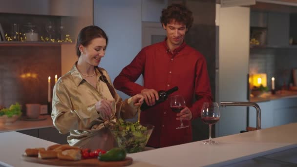 Dos personas cariñosas bebiendo vino y cocinando ensalada en casa — Vídeos de Stock