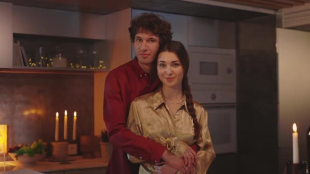 Romantikus pár ölelkezik a konyhában, és a kamerába néz — Stock videók