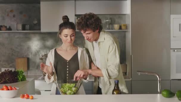 Manželka míchání salát zatímco manžel líbání a objímání ji — Stock video