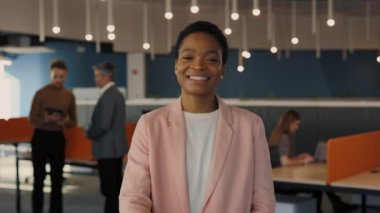 Çok kültürlü, başarılı bir kadının portresi. Kumral saçlı, kameraya bakan ve ofis binasında dururken selamlaşmak için elini uzatan bir kadın. İnsan ve kariyer kavramı.