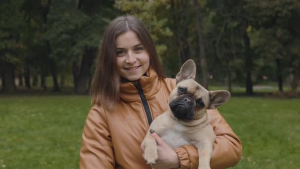 Mujer feliz posando en el parque con bulldog francés en las manos — Vídeo de stock