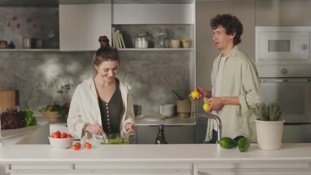 Ženatý pár vaření salát a brát zábavu na kuchyni — Stock video