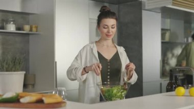 Kadın kocasıyla mutfakta salata pişiriyor.