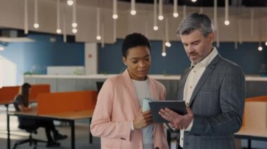 Tarz sahibi iki farklı insan iş merkezinde birlikte durup ortak projeyi tartışıyor. İş arkadaşları kahve içiyor, dijital tablet kullanıyor..