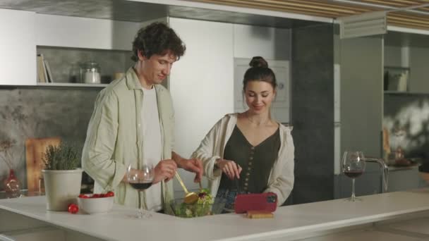 Hombre y mujer cocinando en la cocina y usando teléfono inteligente — Vídeo de stock