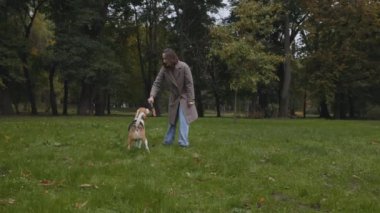 Parkta köpeğiyle oynamak için tahta sopa kullanan bir kadın.