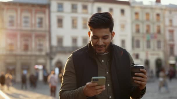 Indisk man läser några goda nyheter på mobil utomhus — Stockvideo