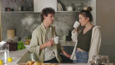 Evli çift evde öpüşüyor, konuşuyor ve kahve içiyor.