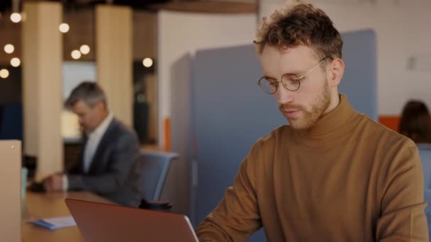 Cintura para cima vista retrato do homem caucasiano digitando no teclado do laptop enquanto trabalhava com documentos no escritório moderno. Conceito de empresários. — Vídeo de Stock