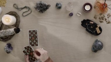 New York, ABD - 1 Mayıs 2021: Bir sürü mumu olan falcı kadının üst görüntüsü ve bir tarot kartına konan tahminler. Astroloji ve okültizm kavramı.
