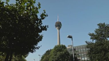 DÜKSELDORF, GERMANY - 1 Temmuz 2021: Rheinturm veya Rhine Kulesi, Almanya 'nın Düsseldorf kentindeki yüksek beton telekomünikasyon kulesi. Düşük açı görünümü, arkaplanda mavi gökyüzü.