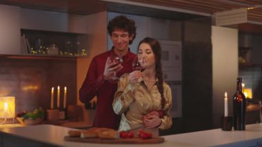 Romantik çift şarap içiyor ve mutfağa sarılıyorlar.