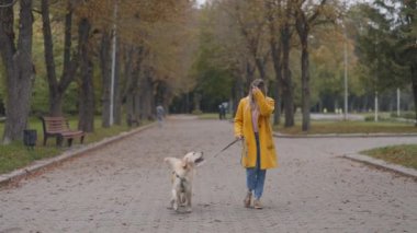 Fransız av köpeğiyle şehir parkında yürüyen bir kadın.