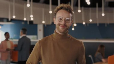 Kendine güvenen genç iş adamının portresi şık giysiler içinde kameraya bakarken içeride duruyor. Modern ofis arka planda açık alan. Erkek portresi kavramı.