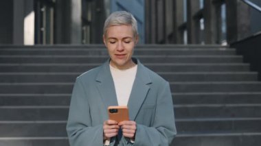 Sokakta akıllı telefon kullanan olgun bir iş kadını.