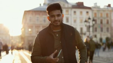 Cep telefonuyla sokakta duran Hintli bir adamın portresi.