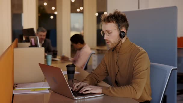 ワイヤレスヘッドセットを装着した笑顔の白人男性がノートパソコンで会議ビデオ通話を行います。男性プロコールセンターエージェント,人事マネージャー持っている距離ウェブカメラチャットジョブインタビューオンコンピュータにオフィス. — ストック動画