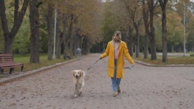 Parkta köpeğiyle gezmek için tasma kullanan bir kadın.