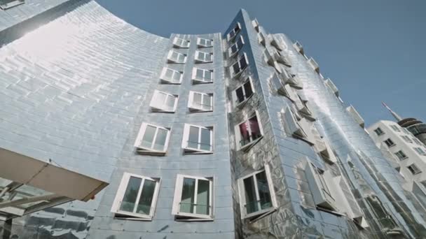 DUSSELDORF, GERMANY - 1 июля 2021: Знаменитое блестящее металлическое здание Neuer Zollhof в Media Harbor Medienhafen, спроектированное Фрэнком О. Гери, завершено в 1998 году. Зрелищная постмодернистская архитектура. — стоковое видео