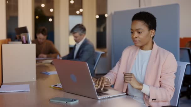 Joven mujer de negocios multirracial sentado en un lugar de trabajo acogedor y trabajando con el ordenador portátil. Freelancer trabajando en proyecto o presentación y regocijo mientras finaliza todos los proyectos. — Vídeos de Stock